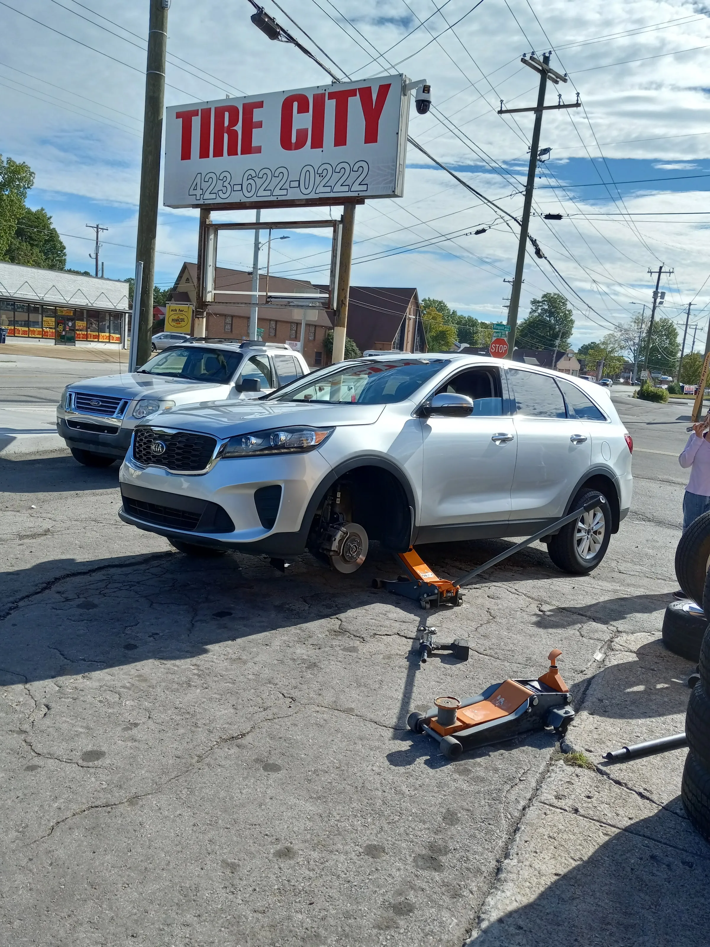 A car raised on a jack stand outside the shop for a tire change