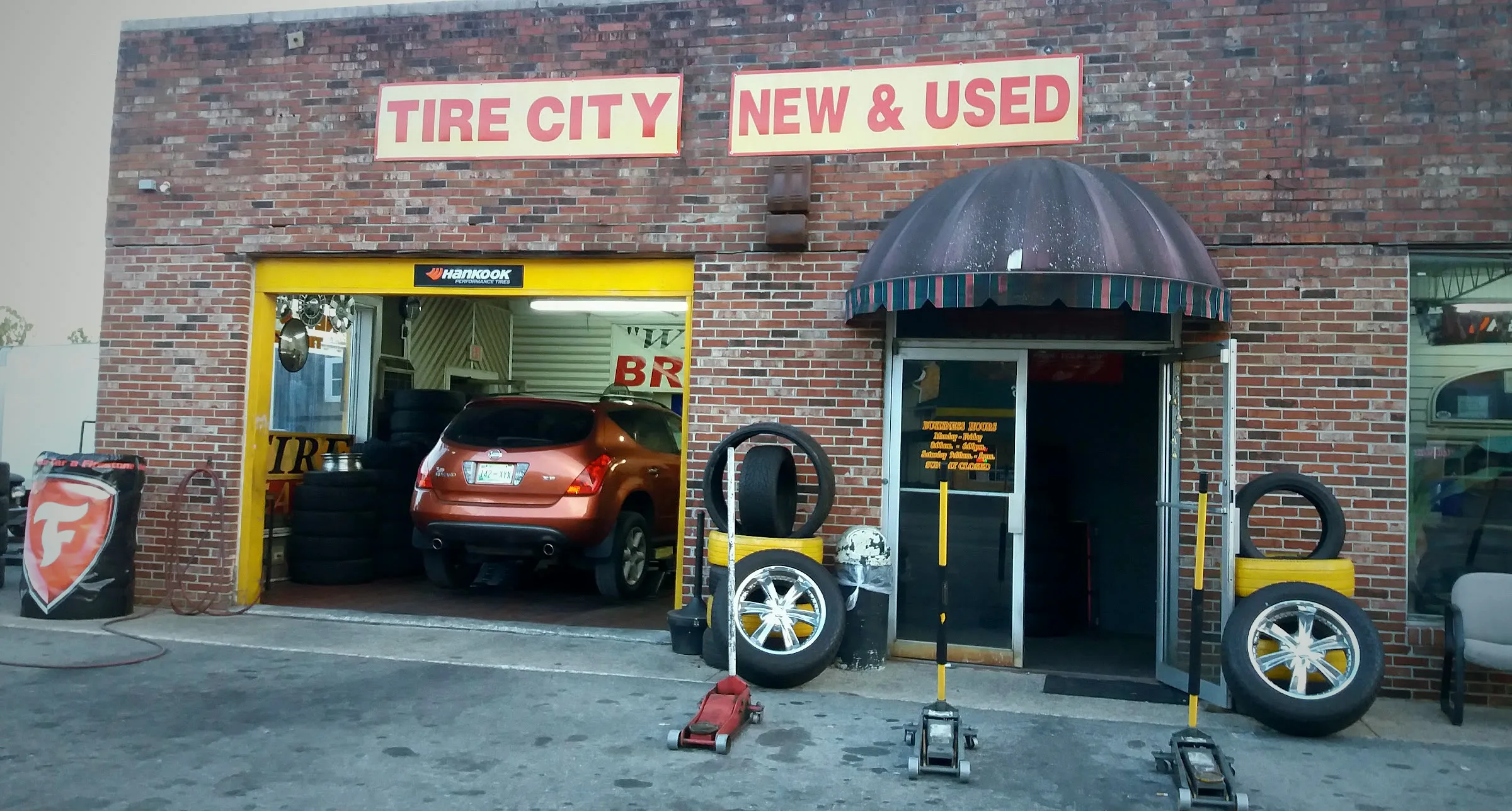Tire City storefront with New and Used Tires signage, awning, and tires on display outside